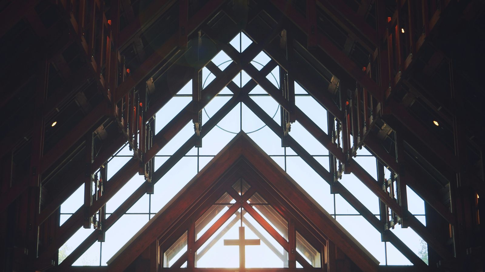 Sunlight through wooden roof beams onto a cross inside a church
